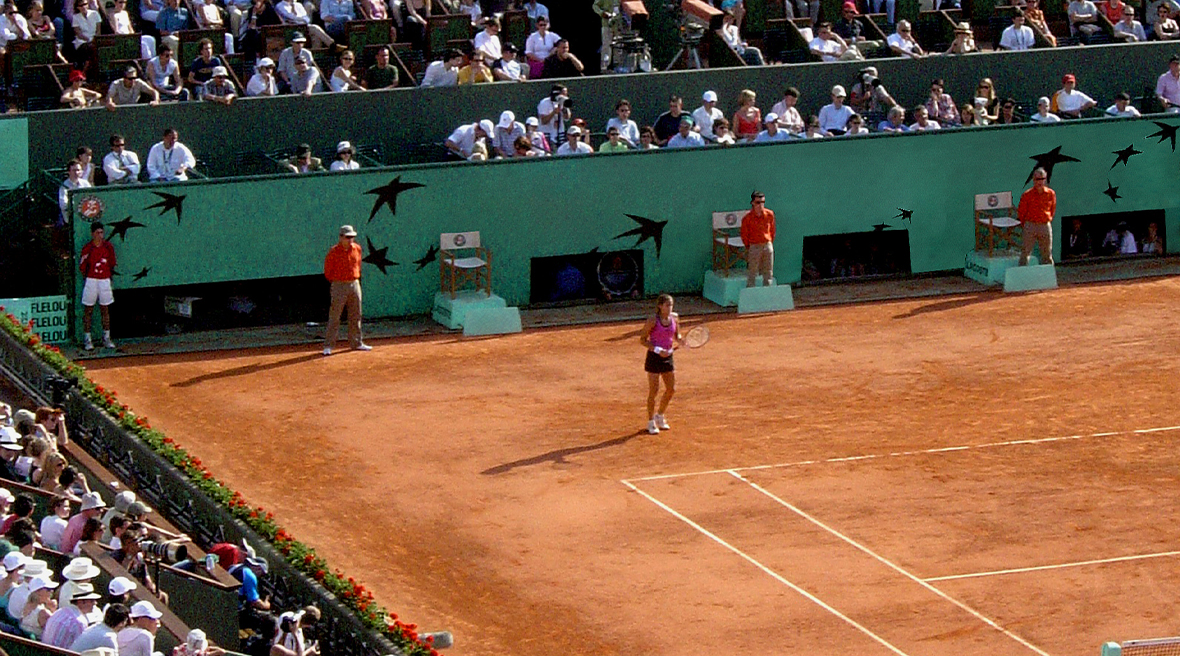 Tennis match on clay court, watched by packed crowds in the stadium